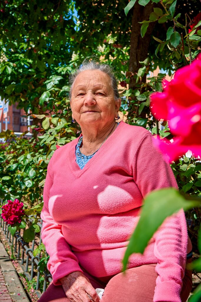 Senior woman sitting in a garden with vibrant flowers in Islas Baleares, Spain.