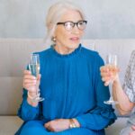Group of aged women with glasses of crystal champagne chatting and looking at each other while congratulating each other