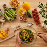 Top view of fresh vegetables and salad preparation on a wooden table, perfect for healthy eating concepts.