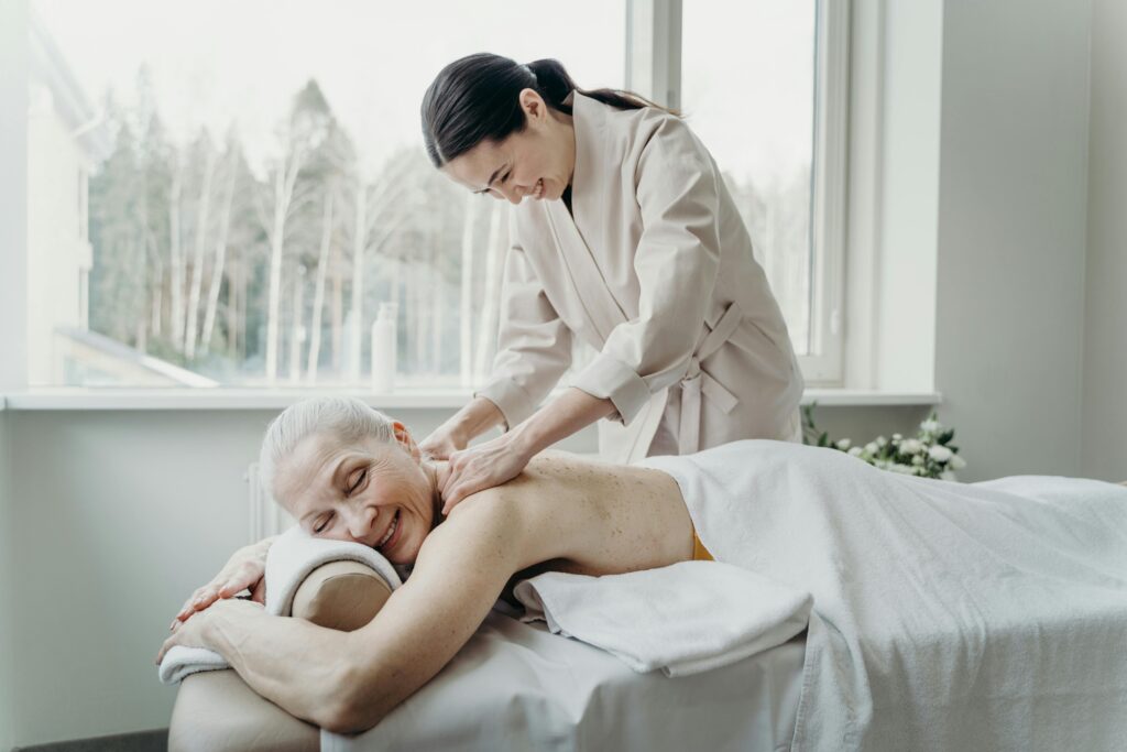 A happy senior woman enjoying a therapeutic massage in a tranquil indoor setting.
