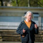 Elderly woman jogging on a bright day, showcasing active lifestyle and wellness in the urban outdoors.