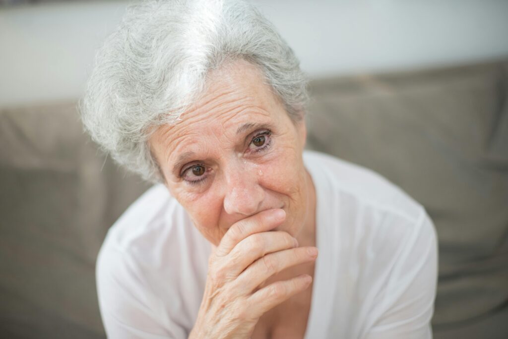 A thoughtful elderly woman with tears in her eyes, conveying deep emotions.