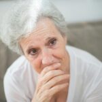 A thoughtful elderly woman with tears in her eyes, conveying deep emotions.